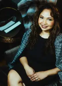 Image of the founder and lead consultant of R. White Consultancy. A young woman with dark brunette hair, olive skin, sitting on a chair. She is wearing a black dress, black and white tweed oversized blazer. Strategic Systems and Data Advisor for Small Businesses and Nonprofits Strategic Advisor helping organizations strengthen systems, data, and decision-making